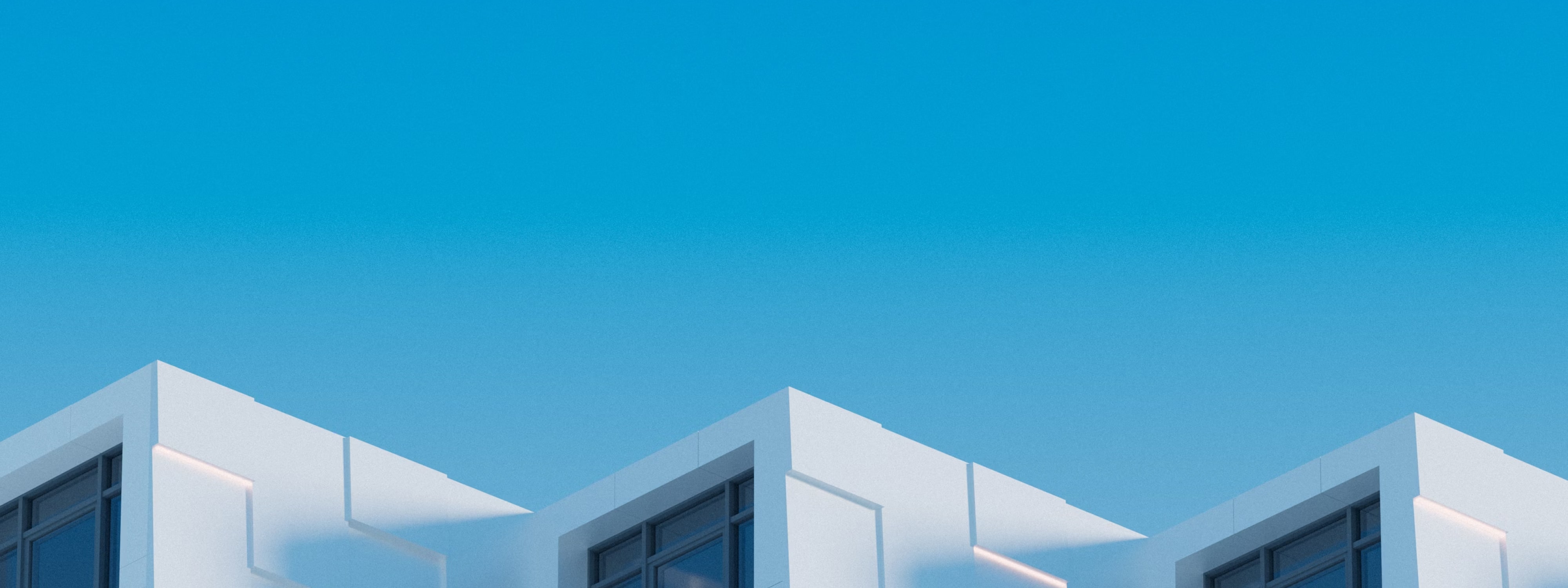 White modern building exteriors against bright blue sky with geometric windows