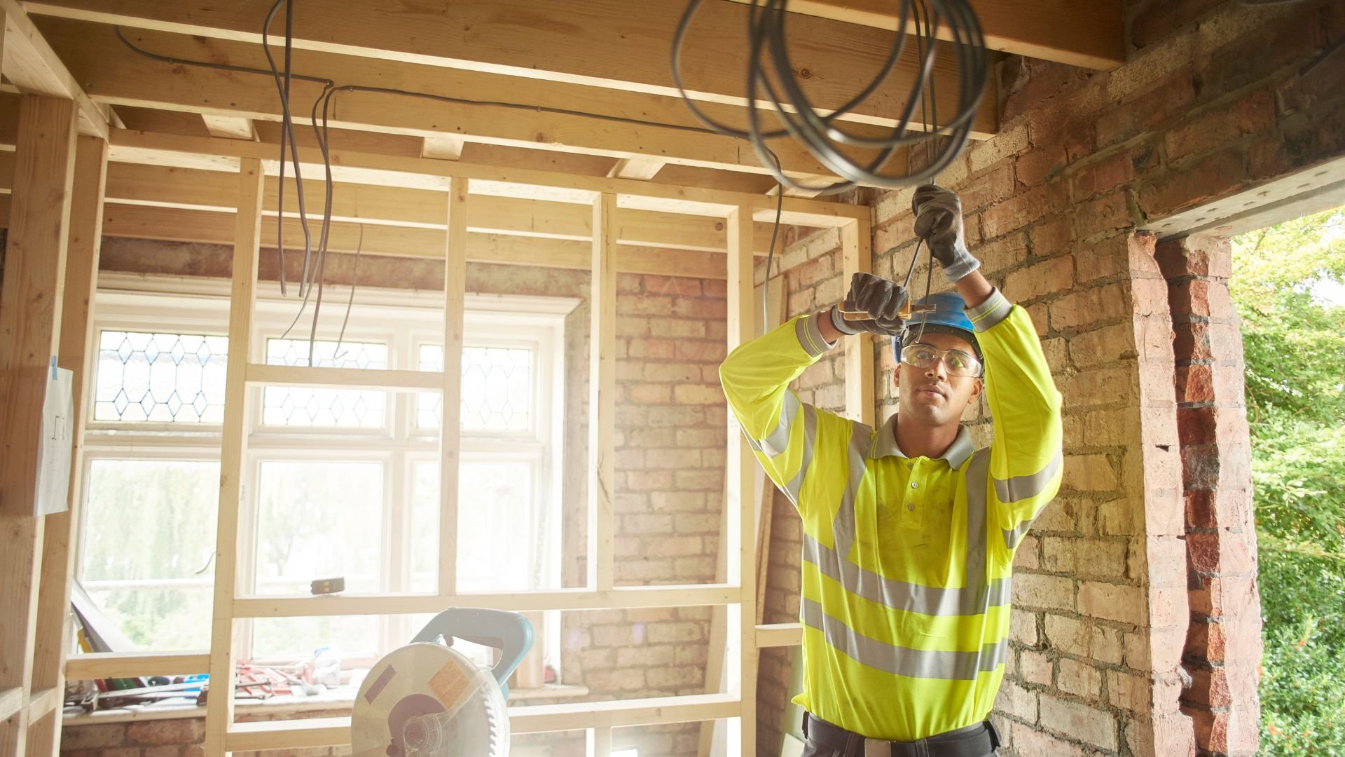Construction worker installing electrical wiring in a partially built interior