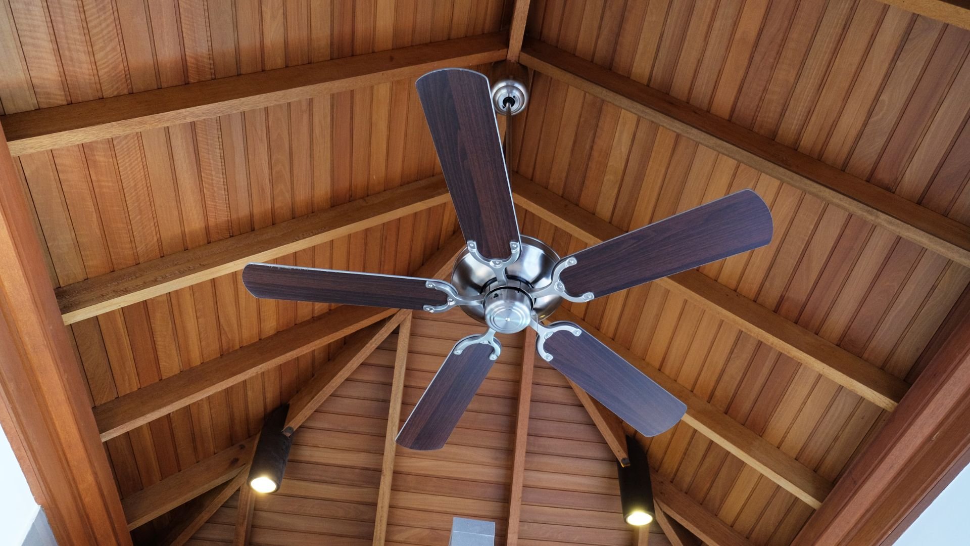 Wooden ceiling with five-blade ceiling fan and recessed lights